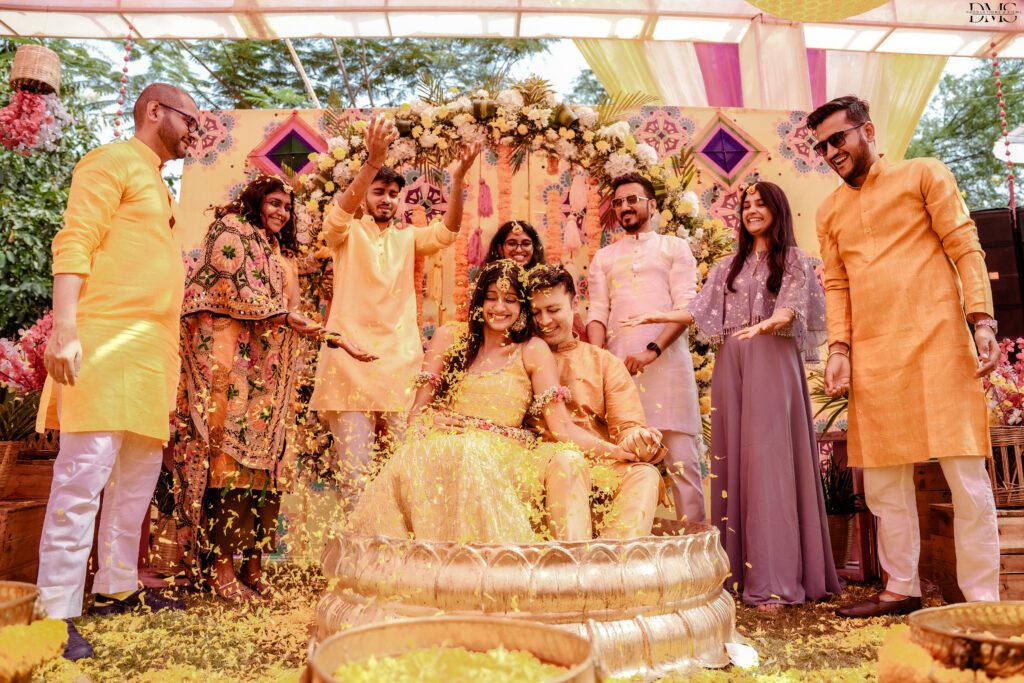 Candid Couple haldi wedding photography by wedding photographers in hyderabad with a family are behind them celebrating Ceremony