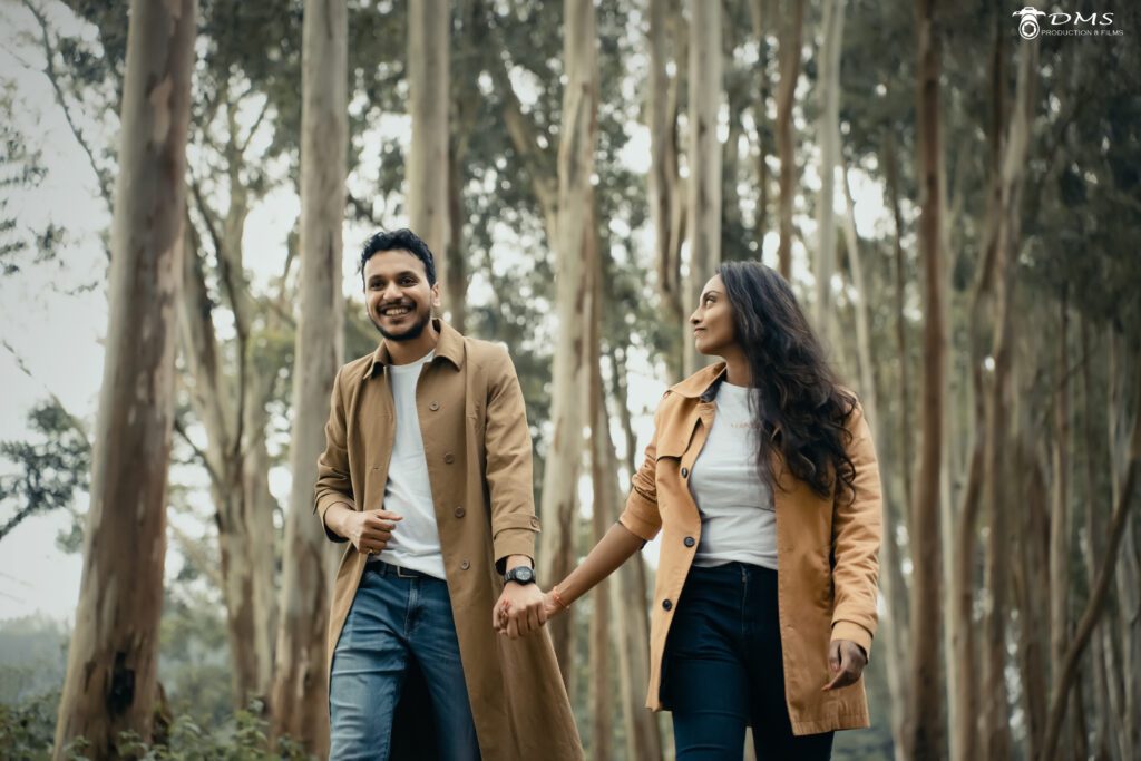 couple walking together in a forest holding their hands and the girl is looking at the boy