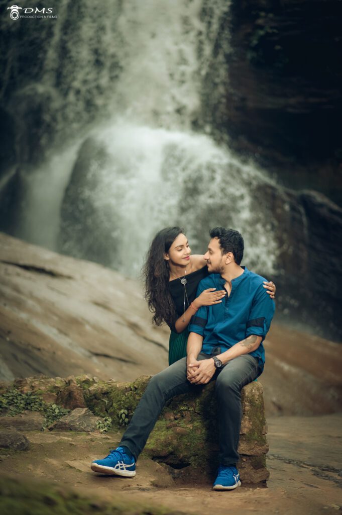 A Pre wedding photoshoot of Couple looking at each other and in backgroung a waterfall is their